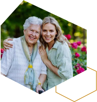 Junge Frau umarmt eine ältere Frau im Garten.