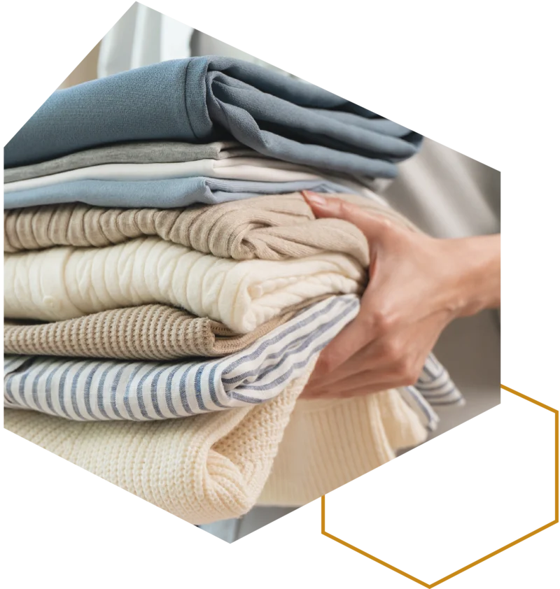 Hände halten einen Stapel frisch gefalteter Wäsche.