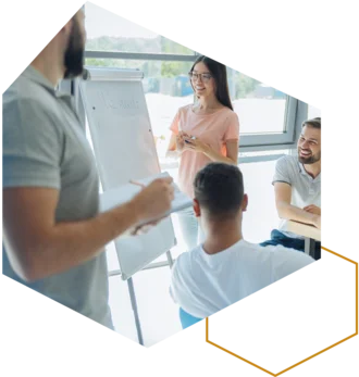 Person hält ein Klemmbrett; Gruppe hört einer Präsentation zu.