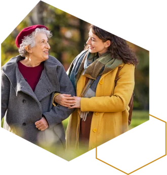 Jüngere Frau begleitet eine ältere Frau beim Spaziergang im Freien.