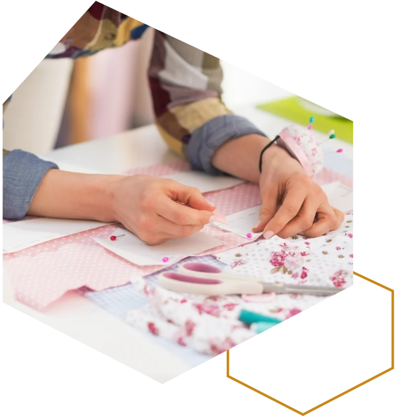 Person arbeitet an einem Nähprojekt mit Stoff und Schnittmuster auf dem Tisch.