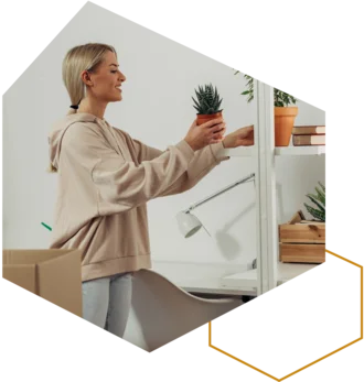 Frau stellt eine Zimmerpflanze in ein Regal beim Einrichten.