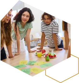 Kinder stehen um einen Tisch mit bunten Karten und Spielmaterial.