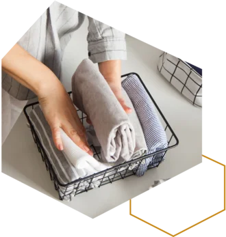 Hände legen gerollte Handtücher in einen Drahtkorb.