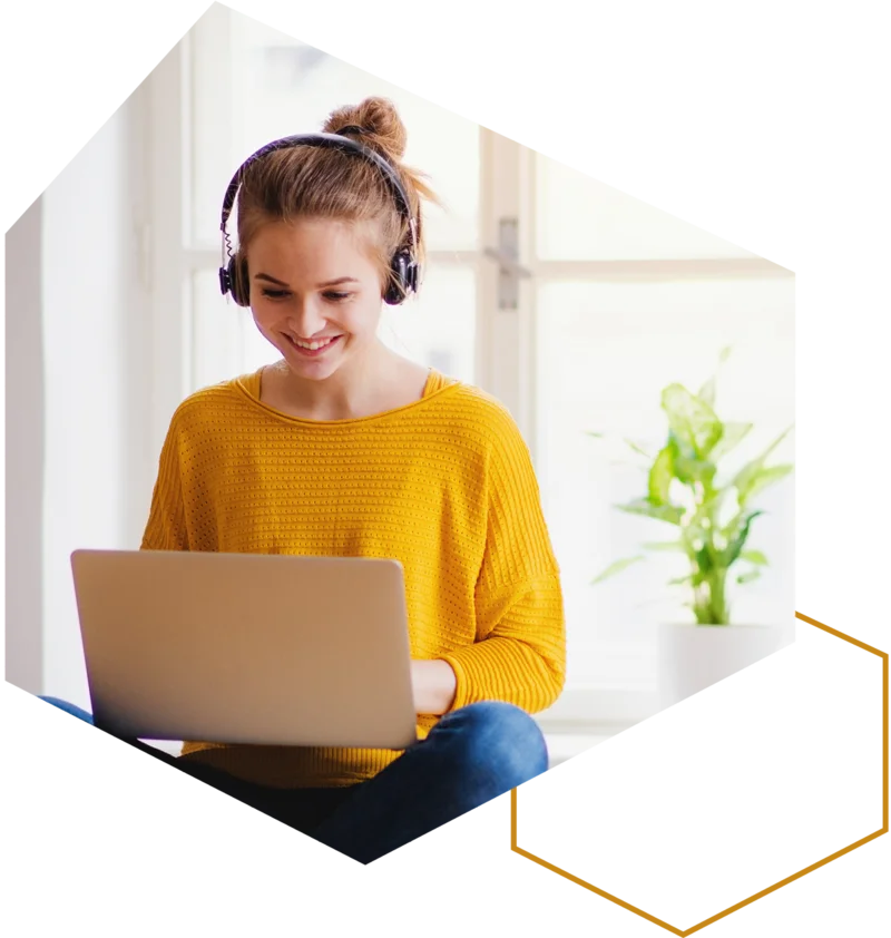 Frau mit Kopfhörern lernt am Laptop zu Hause.