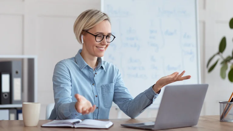 Frau mit Brille erklärt etwas gestikulierend vor einem Whiteboard.