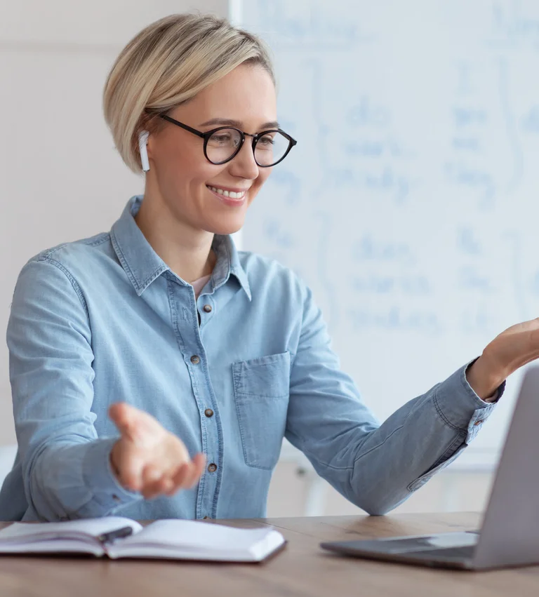 Frau mit Brille erklärt etwas gestikulierend vor einem Whiteboard.
