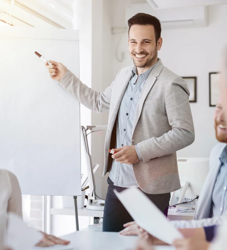 Mann hält eine Präsentation im Meeting mit Team am Tisch.