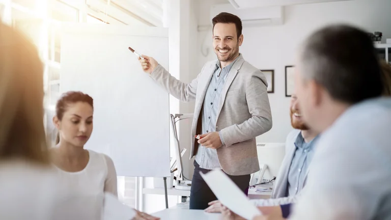 Mann hält eine Präsentation im Meeting mit Team am Tisch.