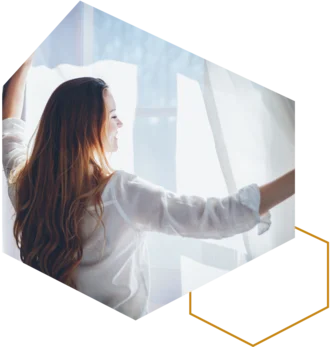 Frau öffnet Vorhänge und lässt Tageslicht ins Zimmer.