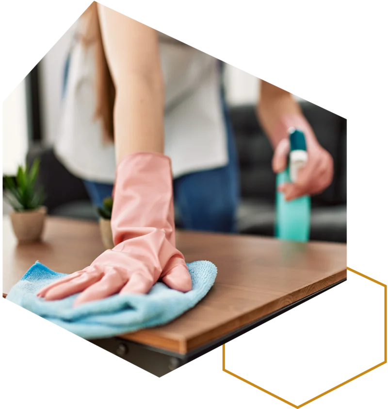 Person wischt einen Couchtisch mit einem Tuch und Reinigungsmittel.