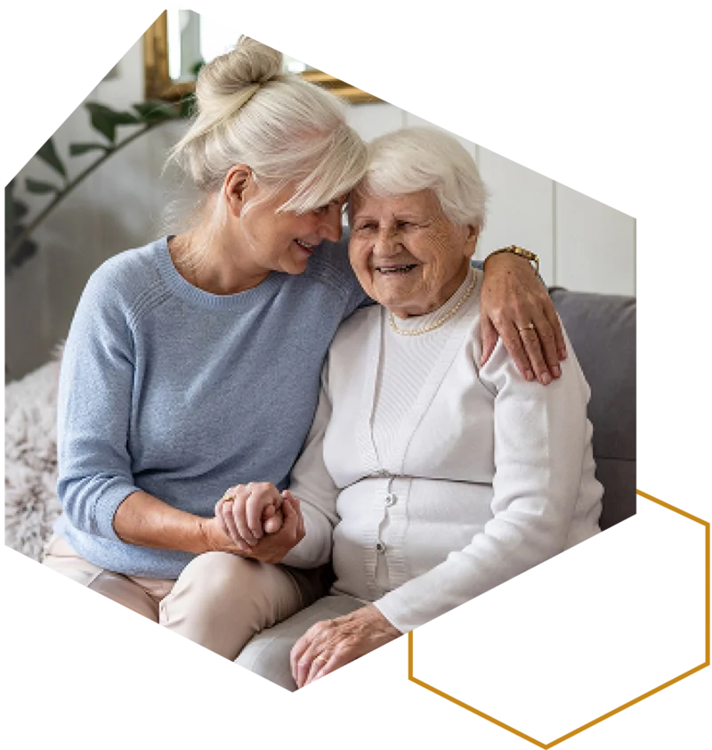 Zwei ältere Frauen sitzen auf dem Sofa und halten sich an den Händen