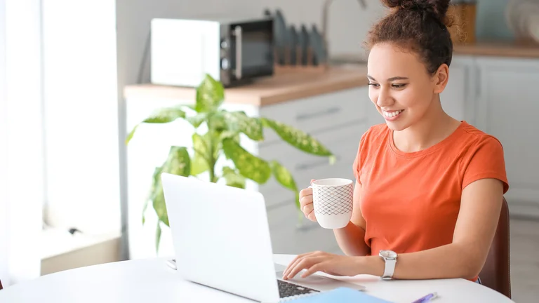 Frau arbeitet am Laptop am Schreibtisch zu Hause.
